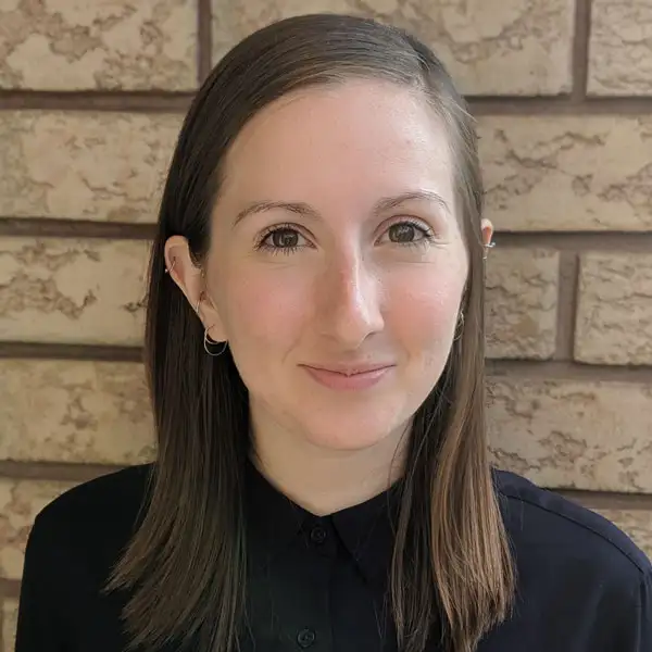 Photo of Ally Weatherall in front of a brick wall in a collared shirt